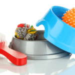 Egy kék és egy szürke tál, piros kefe és színes labdák találhatók rajtuk.