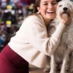Egy nő mosolyogva öleli át a kutyáját egy állatboltban.
