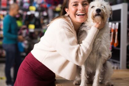 Egy nő mosolyogva öleli át a kutyáját egy állatboltban.