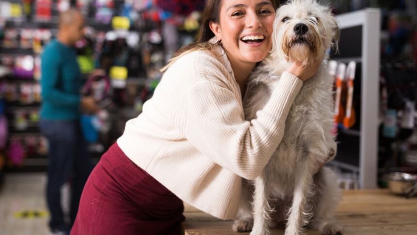 Egy nő mosolyogva öleli át a kutyáját egy állatboltban.